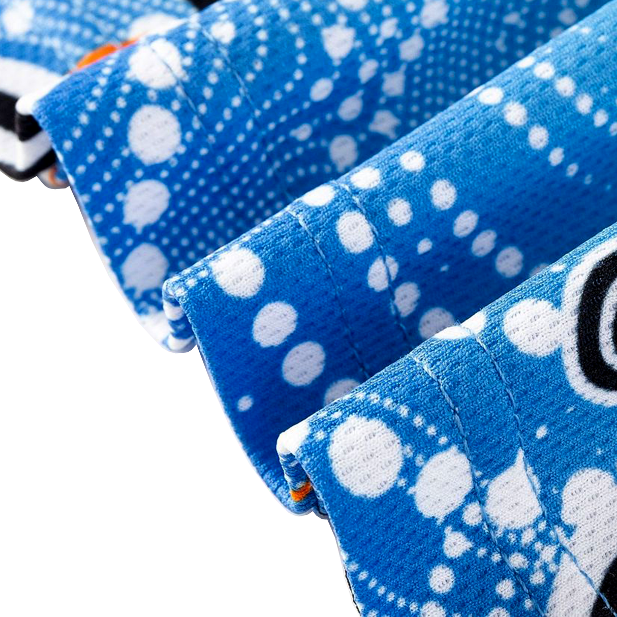 Close-up of three folded blue towels with white dotted patterns, echoing the design of the Sharks Indigenous NRL 25/26 Replica Jersey by Classic Sportswear, and a black letter partially visible on one towel.