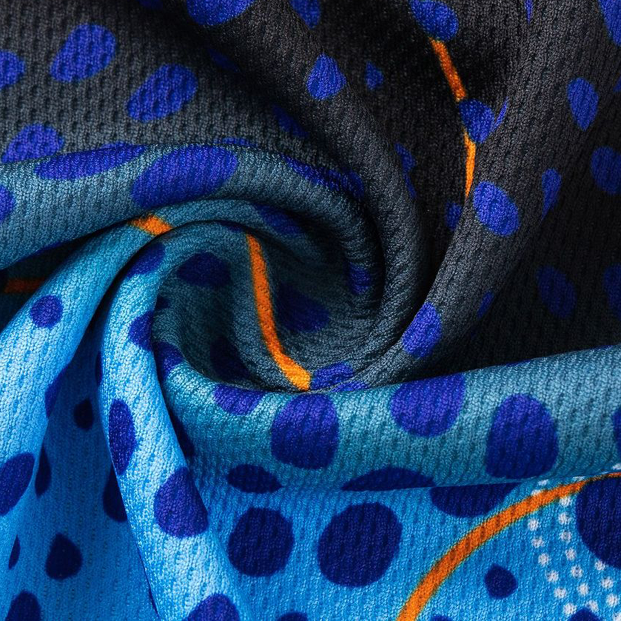 Close-up of twisted fabric from the Sharks Indigenous NRL 25/26 Replica Jersey by Classic Sportswear, showing blue and black dots with curved orange lines on textured material.