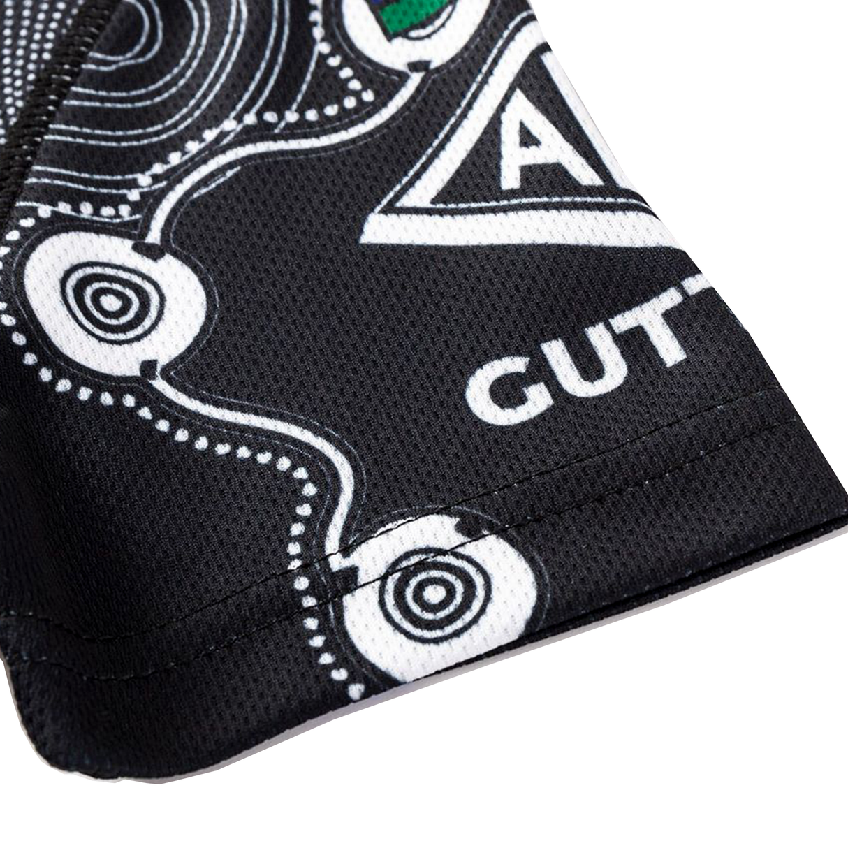 Close-up of black fabric with white geometric and circular patterns, showing partial "GUT" text and triangle design from the Sharks Indigenous NRL 25/26 Replica Jersey by Classic Sportswear.