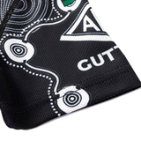 Close-up of black fabric with white geometric and circular patterns, showing partial "GUT" text and triangle design from the Sharks Indigenous NRL 25/26 Replica Jersey by Classic Sportswear.