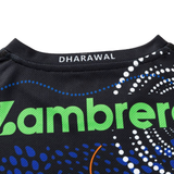 Close-up of the Sharks Indigenous NRL 25/26 Replica Jersey by Classic Sportswear, showing "Zambrero" in green, "DHARAWAL" on the collar, plus blue, white, and orange dotted patterns over black. Ideal for fans.