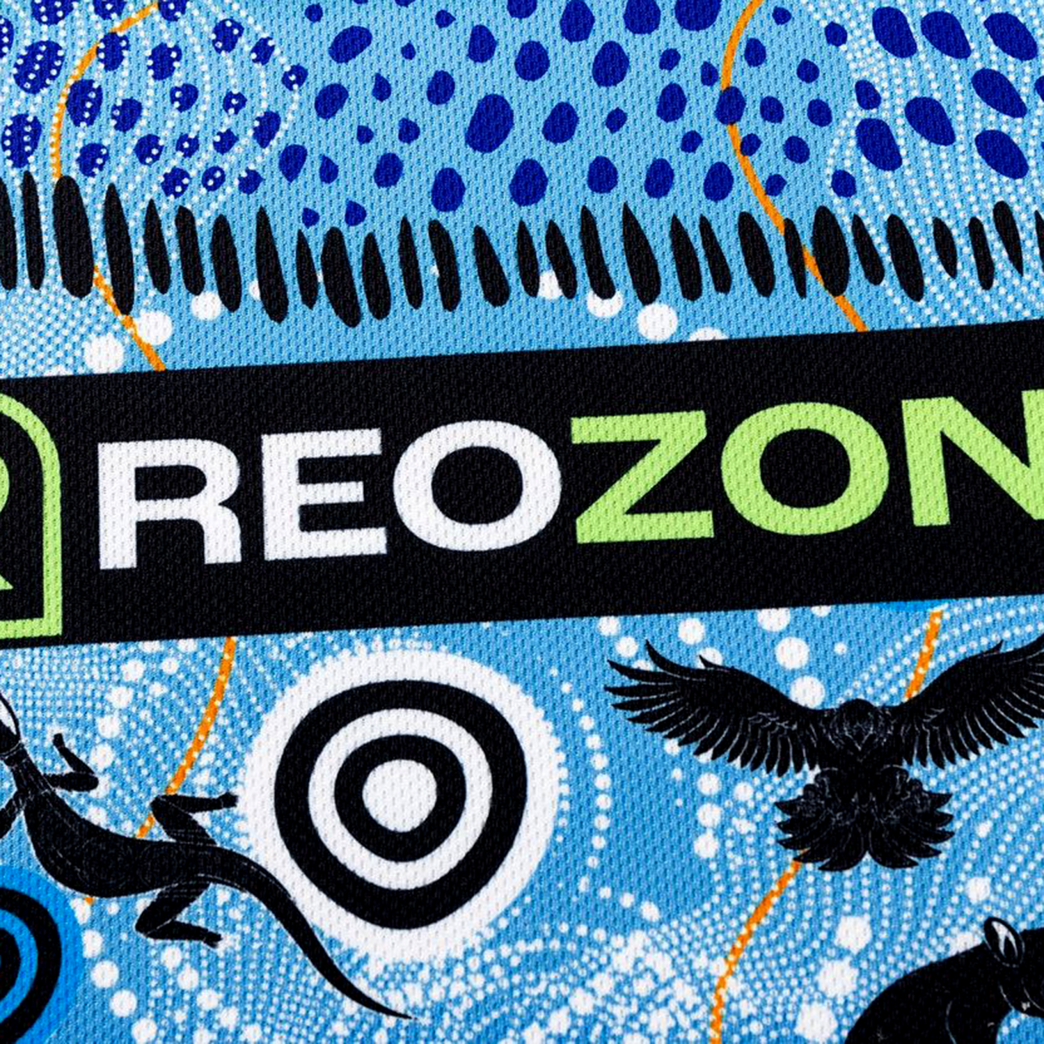 A close-up of the Sharks Indigenous NRL 25/26 Replica Jersey by Classic Sportswear, showing "REOZONE" in bold, blue dotted patterns, black animal silhouettes, and concentric circles inspired by Indigenous design.