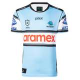 The Sharks NRL 26/27 Replica Home Jersey by Classic Sportswear is light blue with black, white, and blue stripes, featuring the Cronulla Sharks logo, NRL Premiership logo, and "aramex" sponsor across the chest.