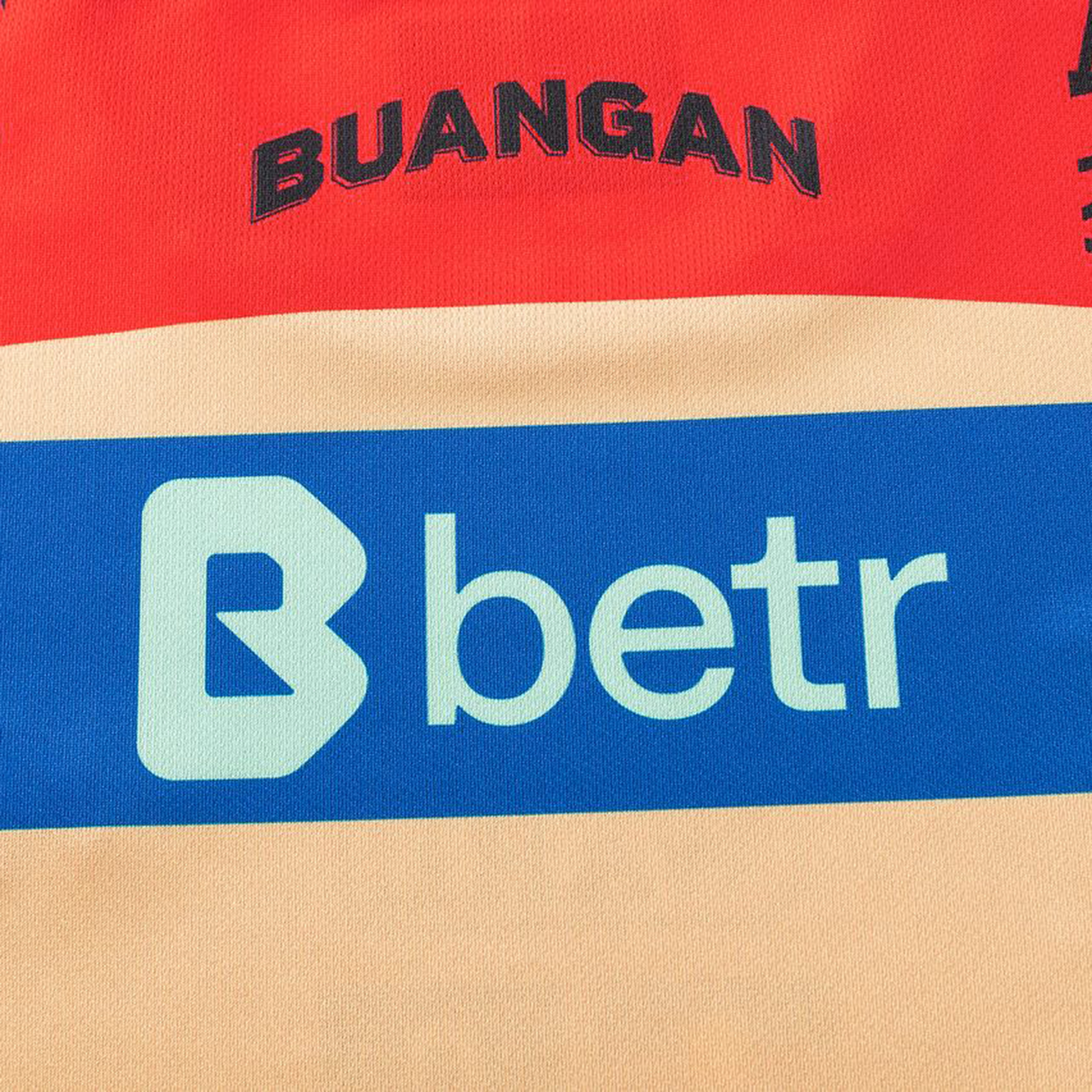 Close-up of fabric from the Dolphins Indigenous NRL 25/26 Replica Jersey by Classic Sportswear, featuring "BUANGAN" in black on red and "betr" in white on a blue band.