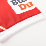 Close-up of the edge of a red and white Dolphins NRL 26/27 Replica Home Jersey by Classic Sportswear, showing partial printed text and stitched seams on a white background.