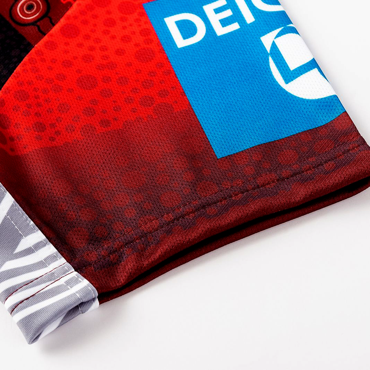 Close-up of the Dragons Indigenous NRL 25/26 Replica Jersey by Classic Sportswear, showing red and black geometric patterns and a blue rectangular "DEICH" logo.