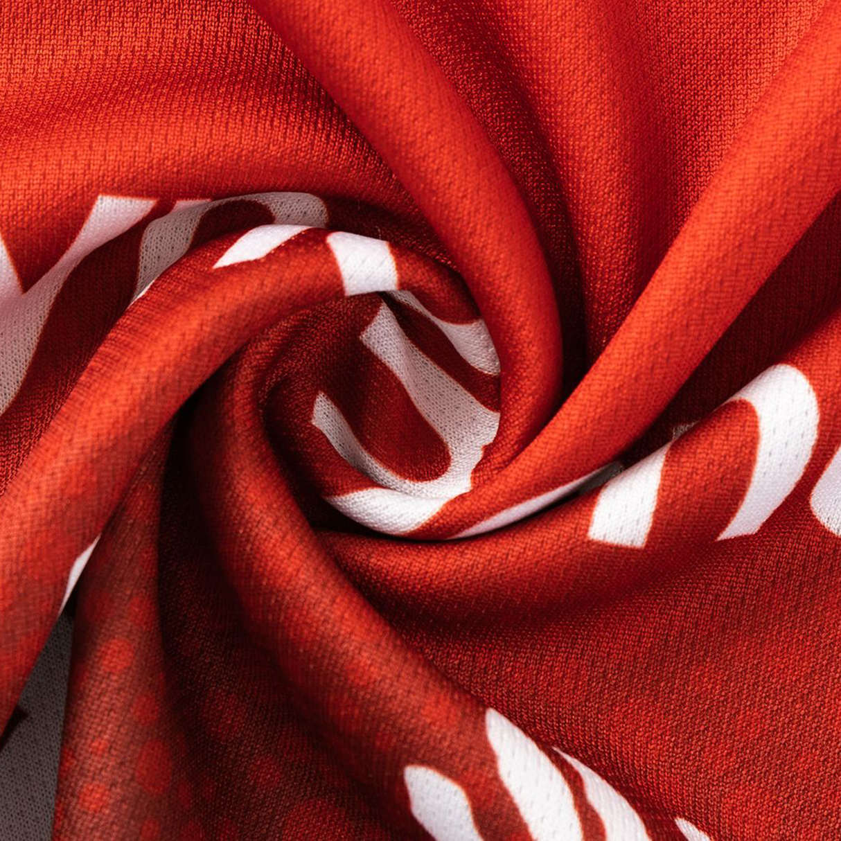 Close-up of red fabric from the Dragons Indigenous NRL 25/26 Replica Jersey by Classic Sportswear, twisted to show its texture and authentic details—a feature of this official NRL replica jersey.