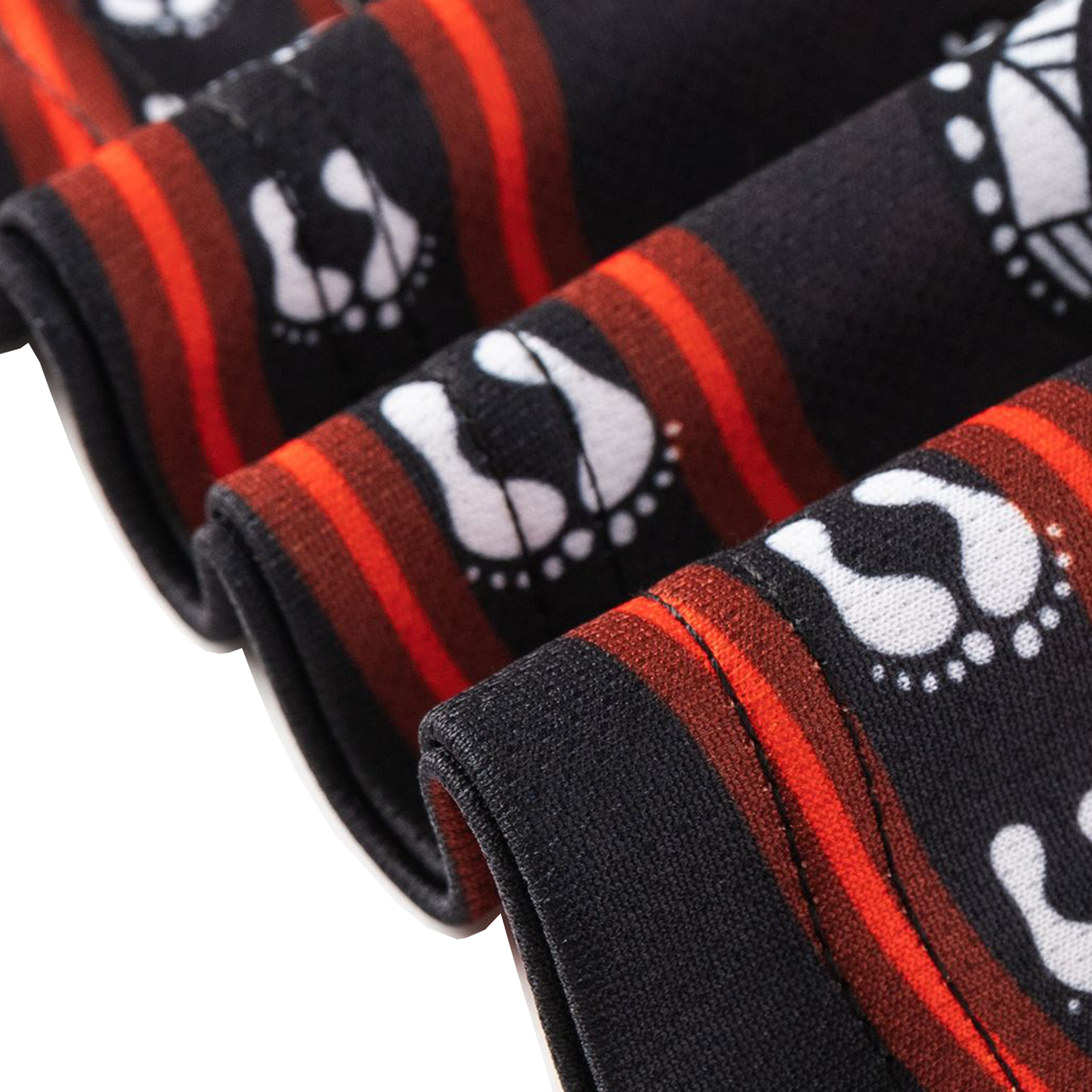 Close-up of folded black fabric with red stripes and white footprint patterns, from the Dragons Indigenous NRL 25/26 Replica Jersey by Classic Sportswear.