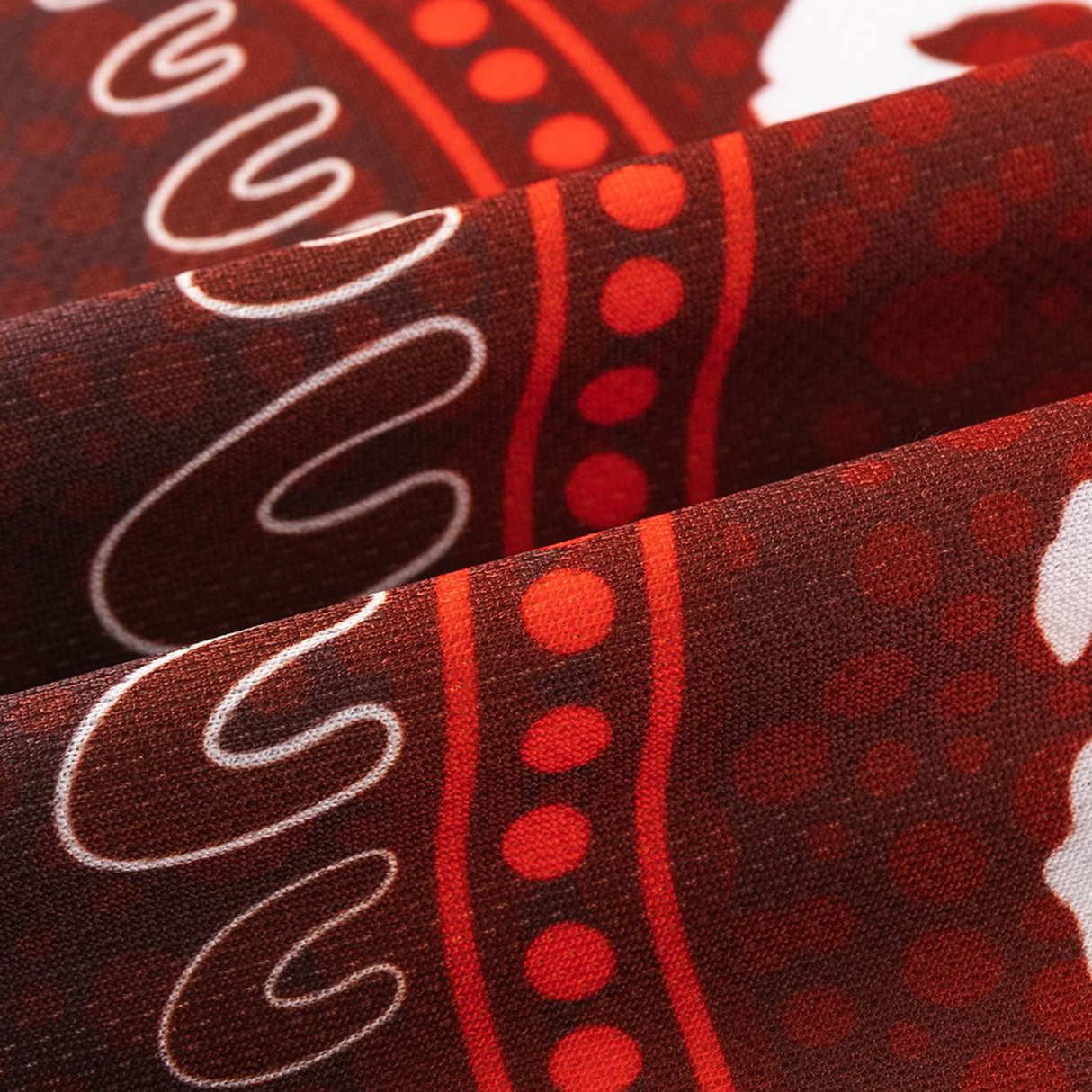 Close-up of folded fabric from the Dragons Indigenous NRL 25/26 Replica Jersey by Classic Sportswear, featuring a red, brown, and white abstract dot and line pattern—a standout collectible for fans of Classic Sportswear.