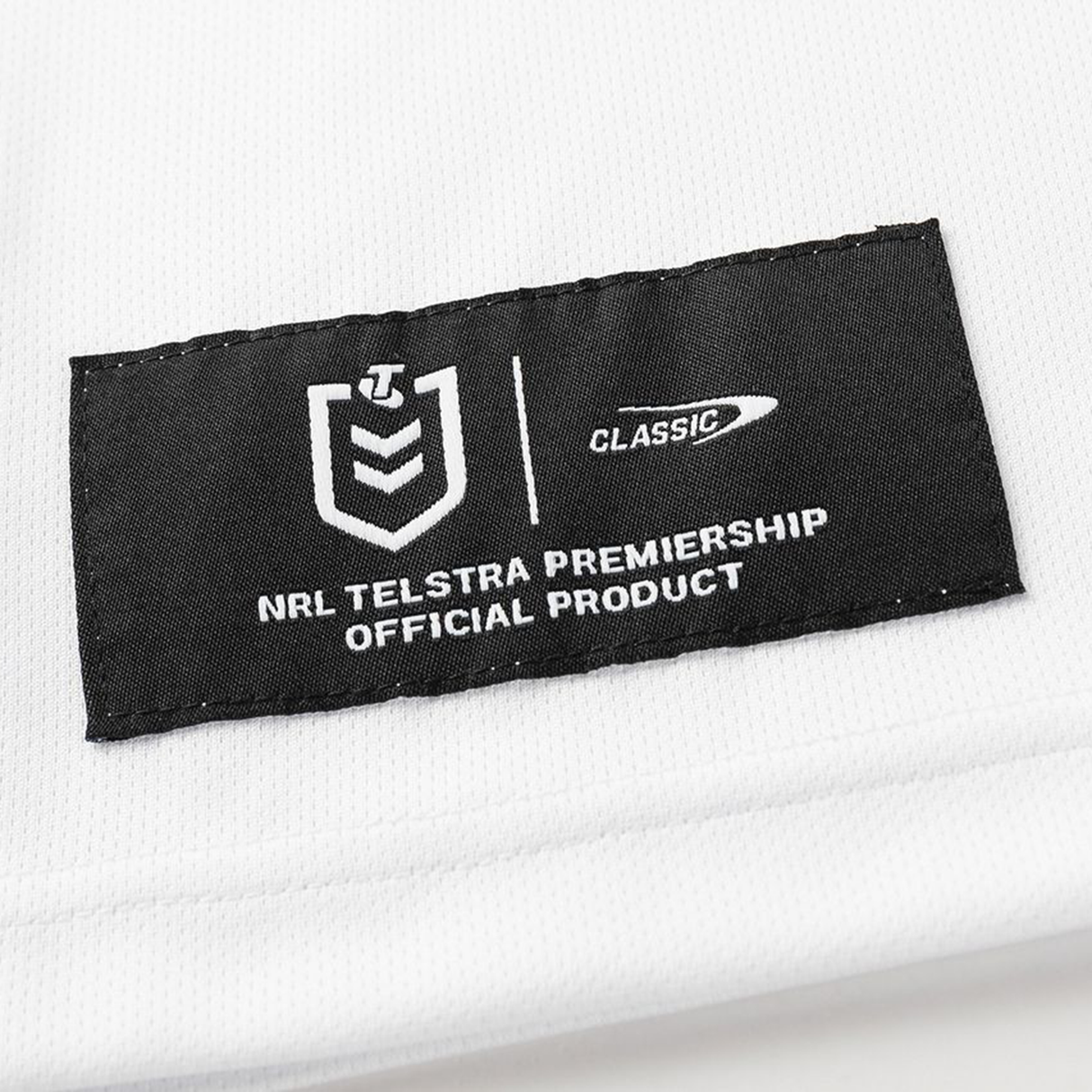 A black label on white fabric reads "NRL Telstra Premiership Official Product" with NRL and Classic Sportswear logos, featured on the Dragons NRL 26/27 Replica Home Jersey by Classic Sportswear.