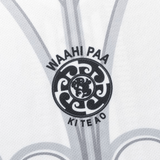 Close-up of a patterned fabric with a detailed black circular emblem and "WAAHI PAA KI TE AO" text, enhanced by sublimated graphics. This design draws inspiration from the NRL Maori All Stars 25/26 Replica Home Jersey by Classic Sportswear, adding authenticity to the elegant piece.