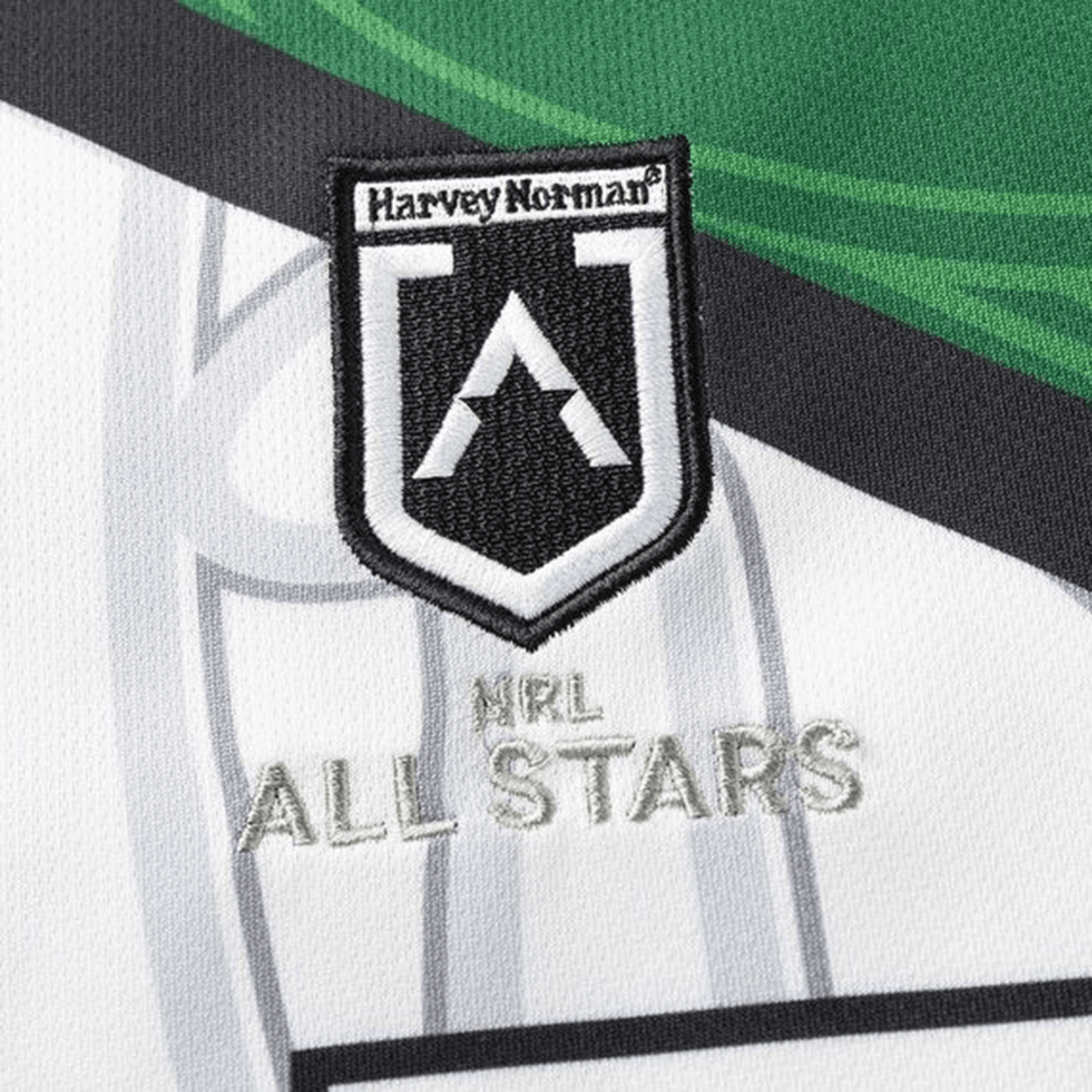 A close-up shows an embroidered patch on fabric with a "Harvey Norman" logo above "NRL All Stars" text, in white, black, and green. The patch is featured on the NRL Maori All Stars 25/26 Replica Home Jersey by Classic Sportswear with antimicrobial wickable material.