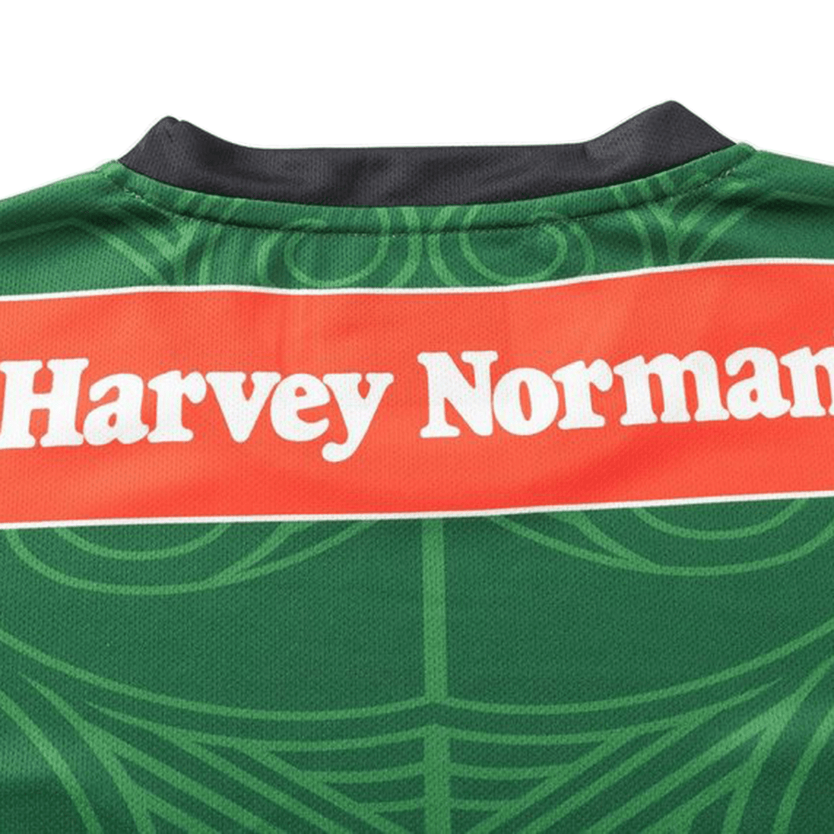 Close-up of the back of a green NRL Maori All Stars 25/26 Replica Home Jersey by Classic Sportswear with a black collar, featuring "Harvey Norman" in white on a red background. The jersey displays vibrant sublimated graphics.