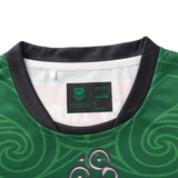 The NRL Maori All Stars 25/26 Replica Home Jersey by Classic Sportswear is a green sports jersey with sublimated swirling patterns, a visible neck tag for size L and brand details, and features anti-microbial wickable fabric for enhanced comfort.