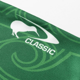 A close-up of the NRL Maori All Stars 25/26 Replica Home Jersey by Classic Sportswear reveals a green fabric with a white kiwi bird silhouette, "CLASSIC," and swirling patterns. Sublimated graphics add depth, while anti-microbial wickable material ensures comfort.