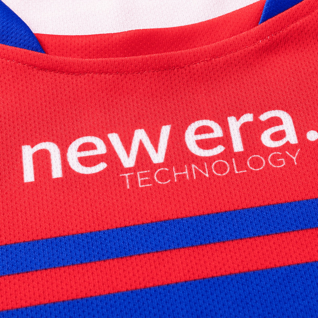 Close-up of a fabric featuring red and blue sections with the words "new era. TECHNOLOGY" printed in white text, reminiscent of a Knights NRL Heritage Jersey by Classic Sportswear worn by the Newcastle Knights.