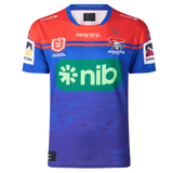 A blue and red sports jersey with the text "nib" displayed prominently on the front. This Knights NRL Heritage Jersey by Classic Sportswear, adorned with several sponsor logos, proudly showcases the team emblem of the Newcastle Knights.