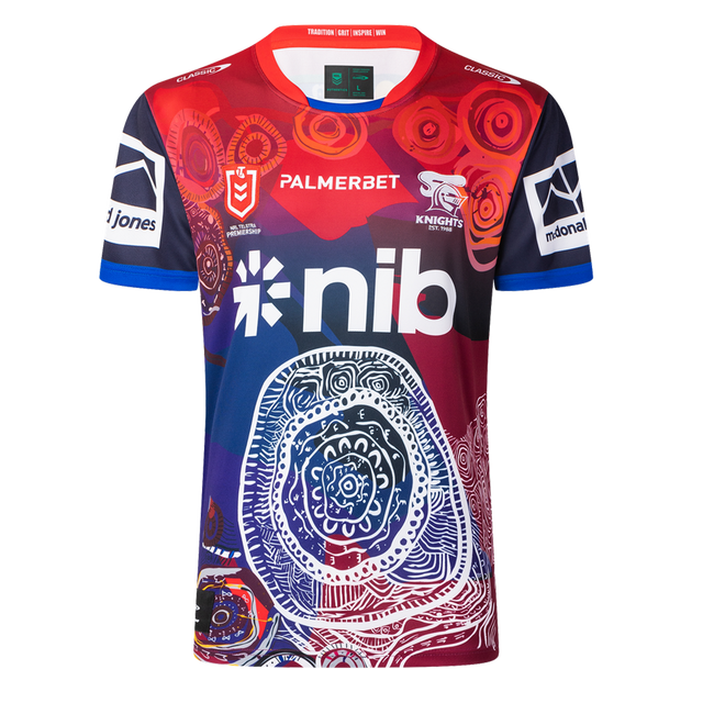The Knights Indigenous NRL 25/26 Replica Jersey by Classic Sportswear features striking red, blue, and white patterns, sponsor logos, and cultural artwork on the front—celebrating team heritage and pride.