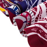 Close-up of fabric with vibrant red, blue, white, and yellow abstract patterns inspired by the Classic Sportswear Knights Indigenous NRL 25/26 Replica Jersey, featuring neatly folded edges.