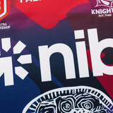 A close-up of the Knights Indigenous NRL 25/26 Replica Jersey by Classic Sportswear, showing the "nib" sponsor, abstract patterns, and partial team logos in red, blue, and purple.