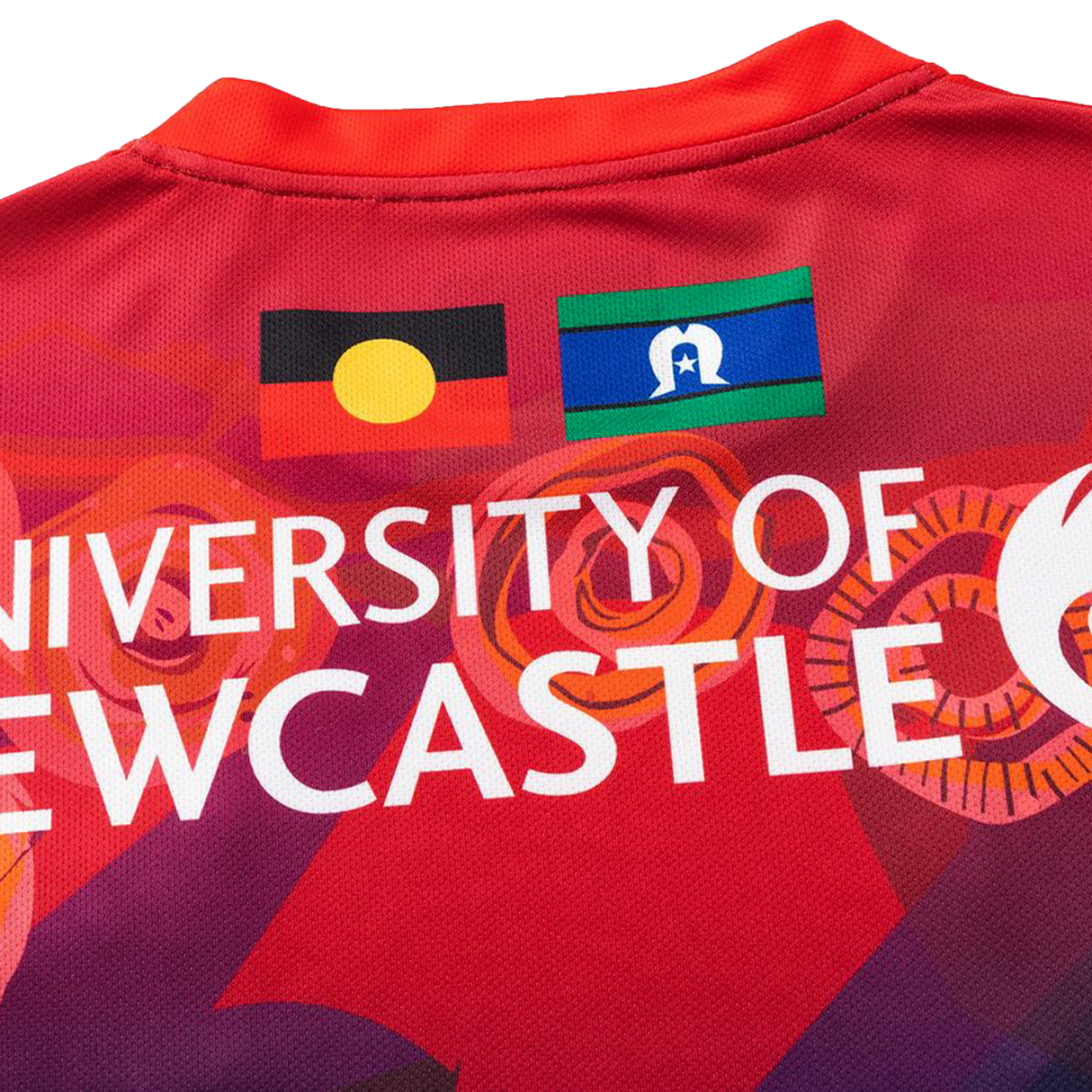 Close-up of the Knights Indigenous NRL 25/26 Replica Jersey by Classic Sportswear, a red shirt with the University of Newcastle logo and Aboriginal and Torres Strait Islander flags.