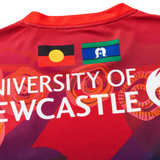 Close-up of the Knights Indigenous NRL 25/26 Replica Jersey by Classic Sportswear, a red shirt with the University of Newcastle logo and Aboriginal and Torres Strait Islander flags.
