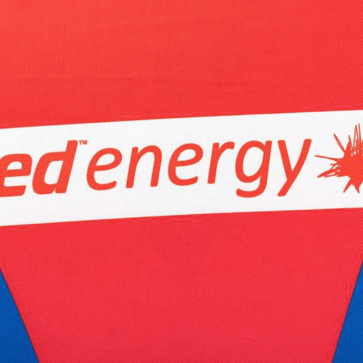 Close-up of the Knights NRL 25/26 Replica Home Jersey by Classic Sportswear, featuring sublimated red and blue graphics with "energy" text and a partial logo, highlighting its dynamic design.