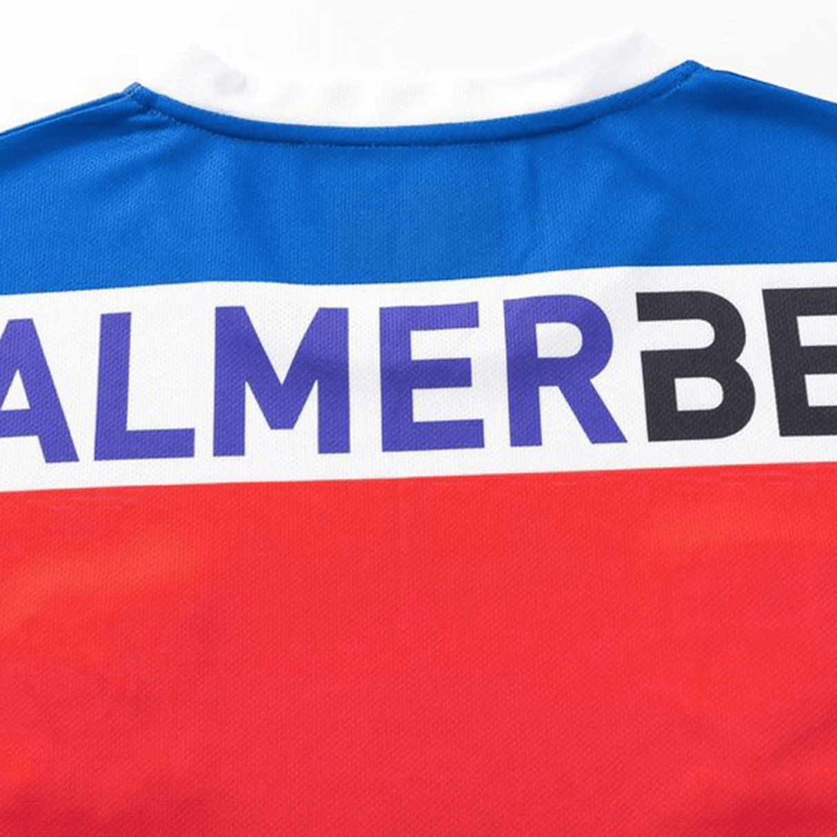 The Knights NRL 25/26 Replica Home Jersey by Classic Sportswear boasts an athletic fit, accented with vibrant blue, white, and red sections. The dynamic design is enhanced by sublimated graphics featuring the partial text "ALMER BE.