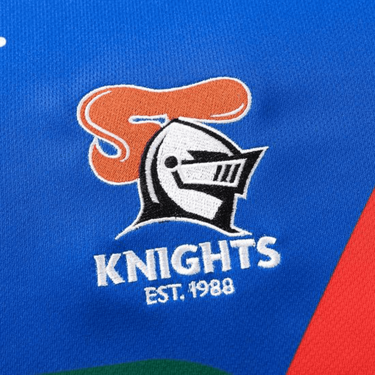 A sublimated logo featuring a knight's helmet with "KNIGHTS" and "EST. 1988" adorns the blue fabric of the Knights NRL 25/26 Replica Home Jersey by Classic Sportswear.