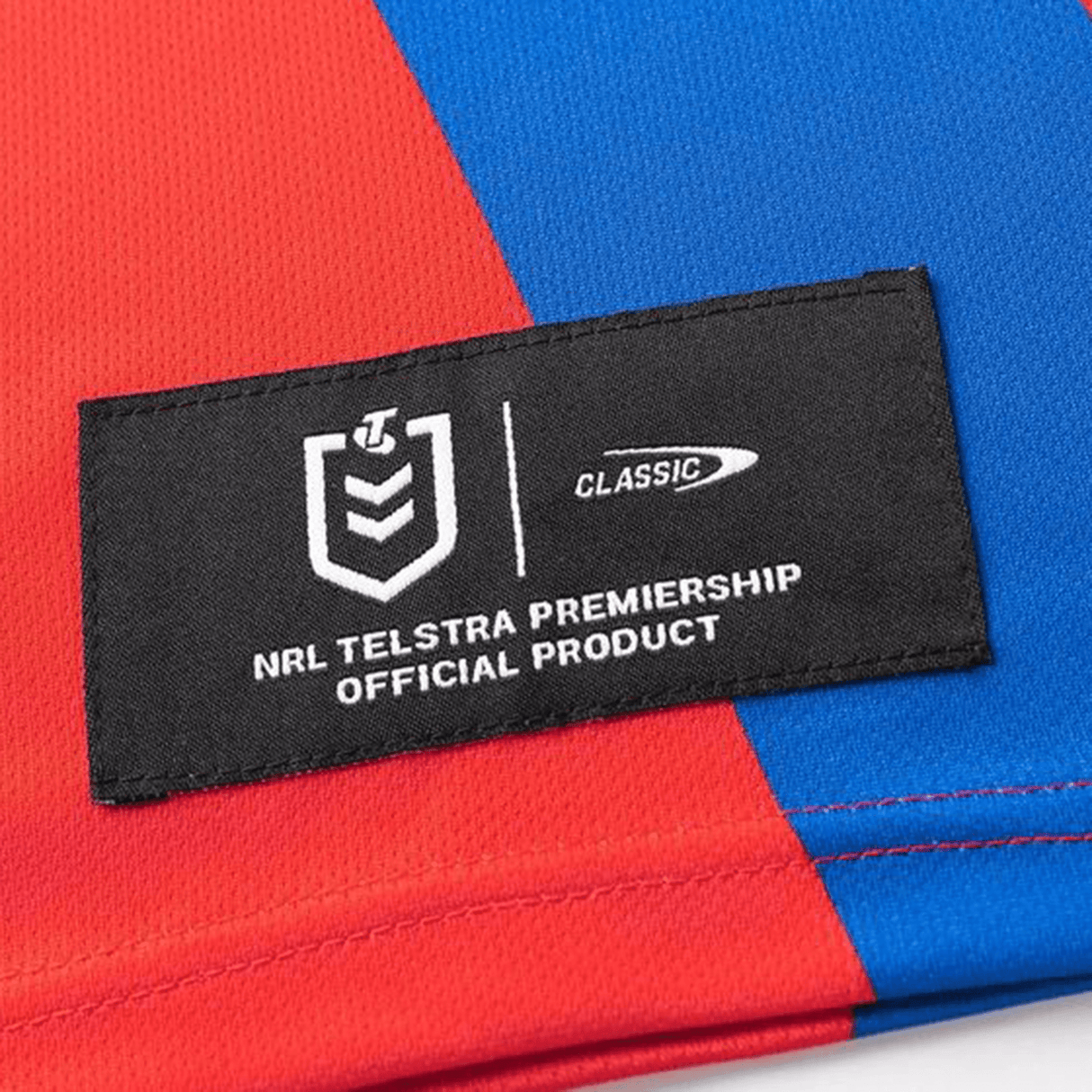 Close-up of the Knights NRL 25/26 Replica Home Jersey by Classic Sportswear, showcasing a red and blue design with sublimated graphics and an NRL Telstra Premiership official product label.