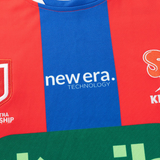 Close-up of the Knights NRL 26/27 Replica Home Jersey by Classic Sportswear, showcasing red and blue vertical stripes, moisture-wicking fabric, and "new era. TECHNOLOGY" printed in bold white text across the front.