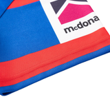 Close-up of a blue, red, and white geometric fabric with partial text "mcdona," from the Knights NRL 26/27 Replica Home Jersey by Classic Sportswear.