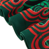 Close-up of folded Rabbitohs Indigenous NRL 25/26 Replica Jersey by Classic Sportswear, featuring a green, red, and black abstract pattern with curved lines and circular shapes.