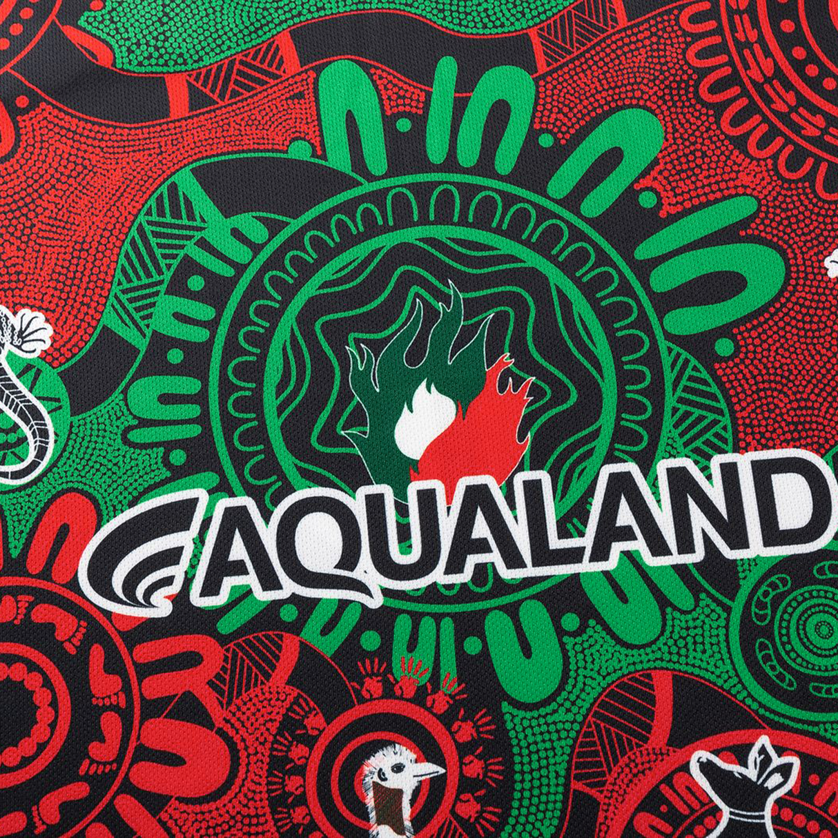 The Rabbitohs Indigenous NRL 25/26 Replica Jersey by Classic Sportswear features a red and green Aboriginal-inspired pattern, "AQUALAND" branding, and stylized animal motifs.