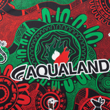 The Rabbitohs Indigenous NRL 25/26 Replica Jersey by Classic Sportswear features a red and green Aboriginal-inspired pattern, "AQUALAND" branding, and stylized animal motifs.