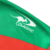 Close-up of a green and red fabric featuring a white kangaroo logo and the words "Rabbitohs NRL 25/26 Replica Home Jersey by Classic Sportswear," reminiscent of the iconic Rabbitohs jersey.
