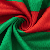 A close-up of fabric with red and green stripes, twisted into a spiral, reminiscent of the Rabbitohs NRL 26/27 Replica Home Jersey by Classic Sportswear.