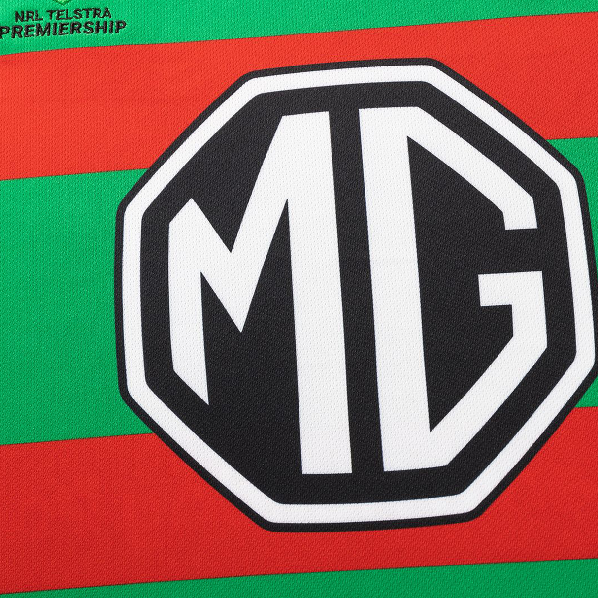 Close-up of the green and red striped Rabbitohs NRL 26/27 Replica Home Jersey by Classic Sportswear, featuring a bold black and white MG logo and a small "NRL Telstra Premiership" text in the corner.
