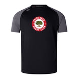 The Chico Oaks Elite Training Tee by WRS Canterbury, in black and gray, uses Vapodri fabrics for comfort and features a circular "Chico Oaks Rugby Club" logo with a tree center. Its elite style is akin to the 3D CCC logo on premium Canterbury Elite Training Tees.