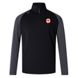 The black and gray long-sleeve quarter-zip pullover features a circular red and white chest logo. As the Chico Oaks Elite First Layer by EMB Canterbury, it's designed for rugby training with VapoDri technology for enhanced comfort and performance.