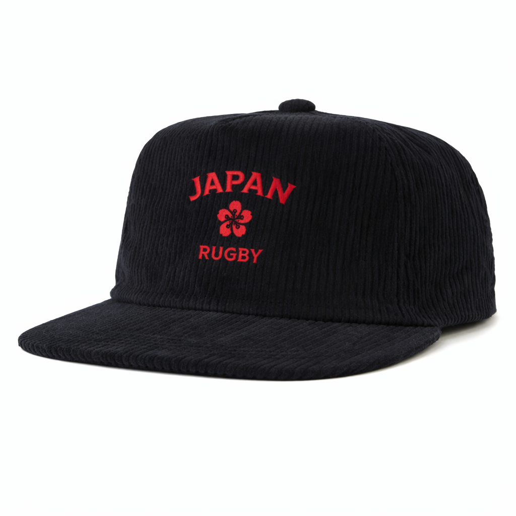 The EMB Weld Nations of Rugby Japan Corduroy Field Trip Cap features black corduroy, red "JAPAN RUGBY" embroidery, and a front flower emblem—adding vintage style to your look.