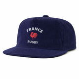 The EMB Weld Nations of Rugby France Corduroy Field Trip Cap is a navy blue flat-brim hat featuring "FRANCE RUGBY" and a red rooster embroidered on the front for an authentic vintage France rugby style.