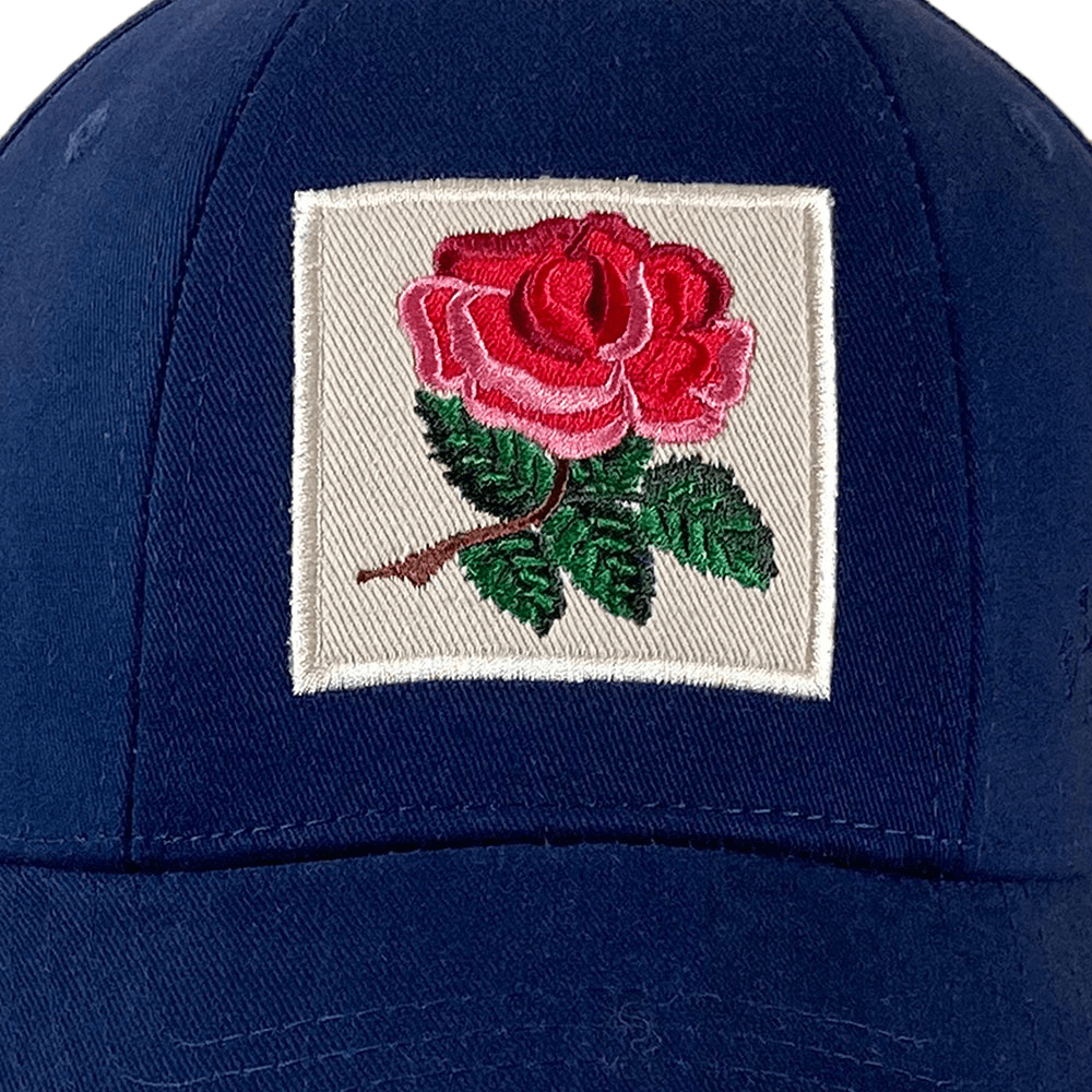 The Ellis Rugby England Rugby 1991 Six Nations Cap by Ellis Rugby, made of organic cotton in Navy blue, showcases an embroidered red rose with green leaves on a white square. It's ideal for Six Nations enthusiasts and echoes the classic England Rugby 1991 style.