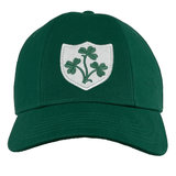 The Ellis Rugby Ireland Rugby 1948 Retro Cap is a green baseball cap made of organic cotton, featuring a white shield emblem with a green three-leaf clover on the front, reminiscent of an Ireland rugby cap.