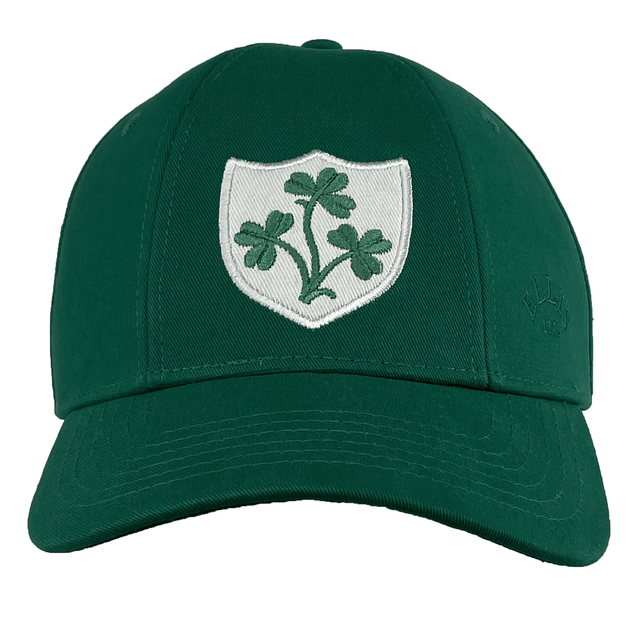 The Ellis Rugby Ireland Rugby 1948 Retro Cap is a green baseball cap made of organic cotton, featuring a white shield emblem with a green three-leaf clover on the front, reminiscent of an Ireland rugby cap.