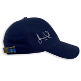 The Ellis Rugby Doddie Weir Scotland Cap by Ellis Rugby is a navy blue baseball cap made from 100% organic cotton, showcasing a white signature on the side. It has an adjustable strap with a green and blue plaid pattern at the back, inspired by classic rugby style.
