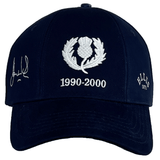 Ellis Rugby's navy blue baseball cap, made from 100% organic cotton, features an embroidered thistle emblem with dates 1990-2000. It includes a white signature on the left and "Ellis 1971" on the right, capturing the spirit of a Doddie Weir Scotland Cap.
