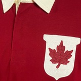 Close-up of the Ellis Rugby Canada Rugby Polo, a red shirt with a white collar and vintage Canadian crest patch featuring "RUGBY 19 02 CANADA" and a red maple leaf, echoing the classic Ellis Rugby style.
