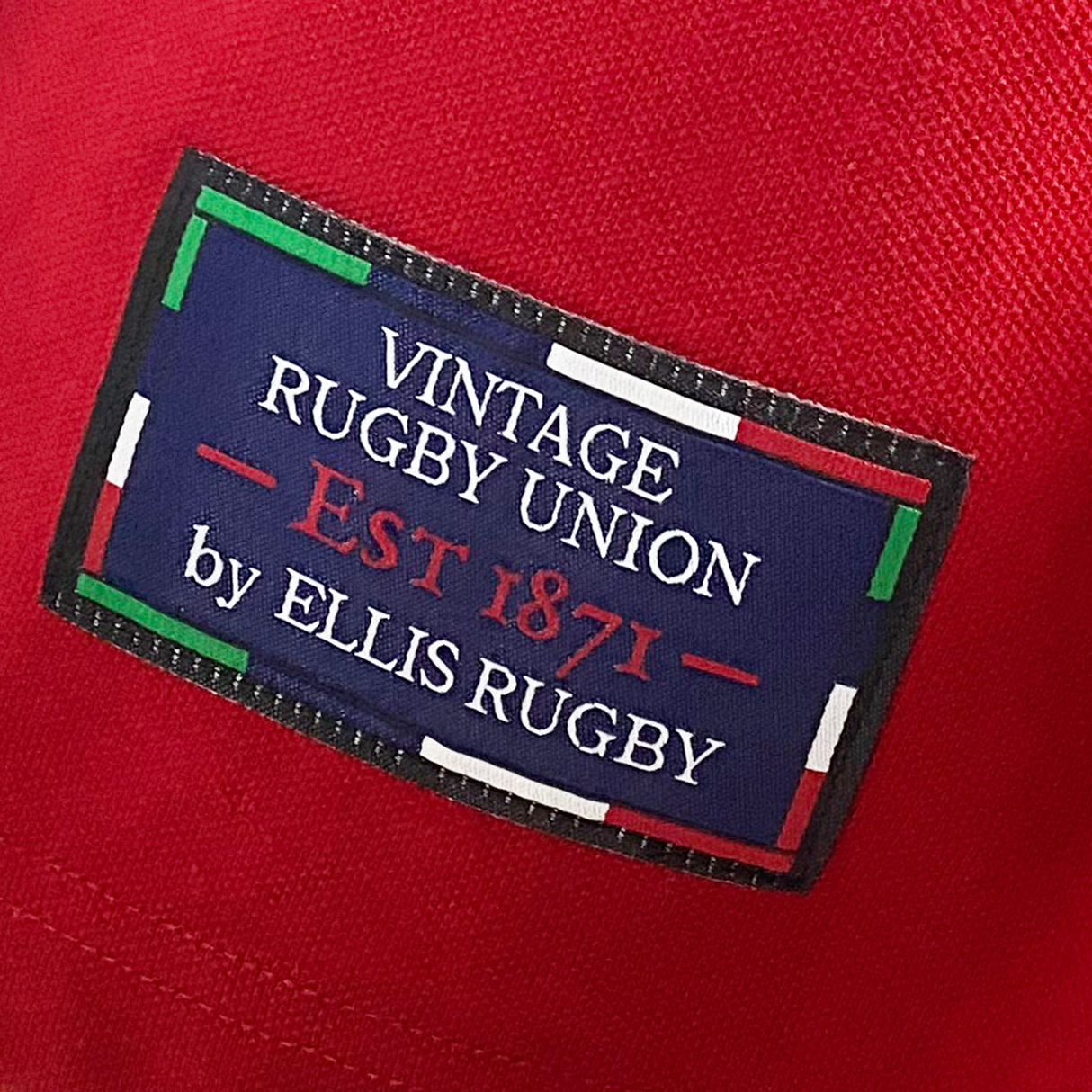 Close-up of a red Ellis Rugby Canada Rugby Polo featuring a blue patch reading "Vintage Rugby Union Est 1871 by Ellis Rugby," bordered by red, green, and white lines, reminiscent of a Vintage Canadian crest for added character.