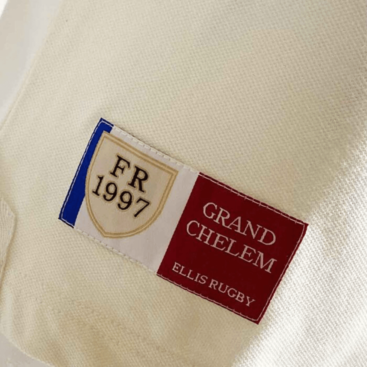 Close-up of a label on the Ellis Rugby 21 Club Collection 1997 France Polo Shirt reading "FR 1997 Grand Chelem Ellis Rugby" with a design of the French flag.